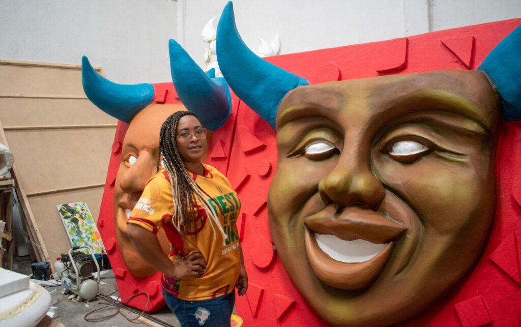 La muralista Ángela Medina junto a las figuras de su carroza La danza de los diablos espejos.