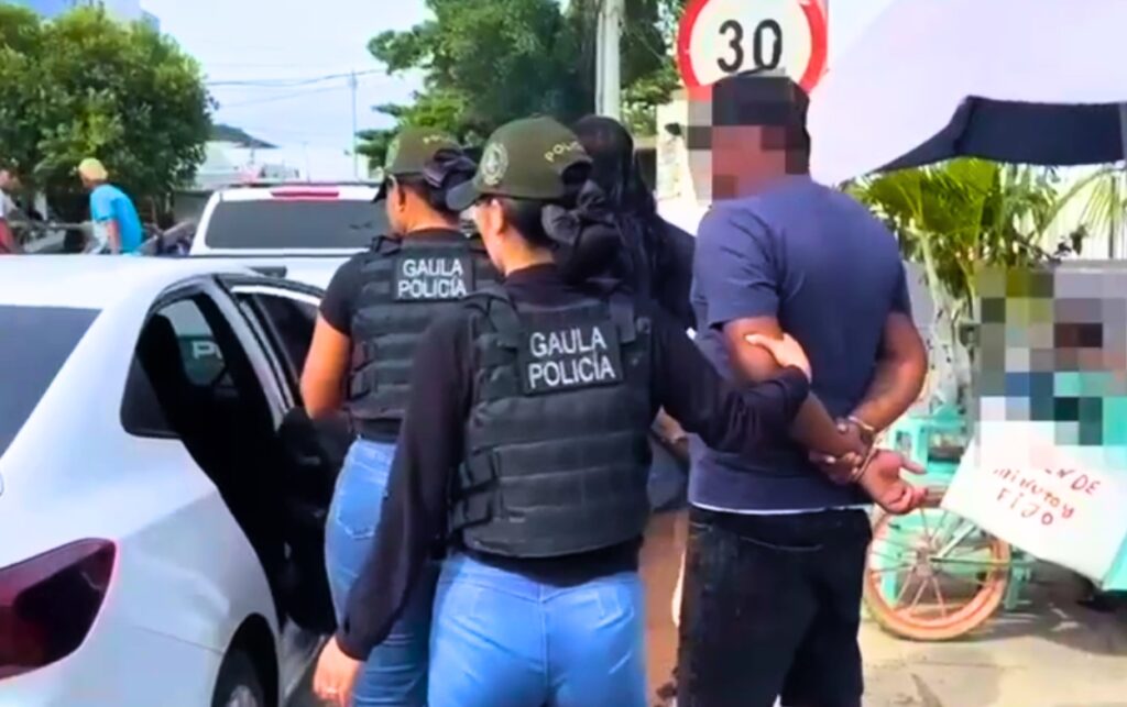 Capturan a 4 presuntos extorsionistas_ agentes del GAULA trasladan a un hombre esposado, con rostro pixelado, hacia un vehículo institucional. 