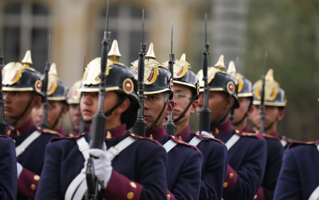 Pelotón de guardias con cascos dorados y fusiles al hombro marcha en formación frente a la Casa de Nariño durante los 94 años de la Casa Militar .