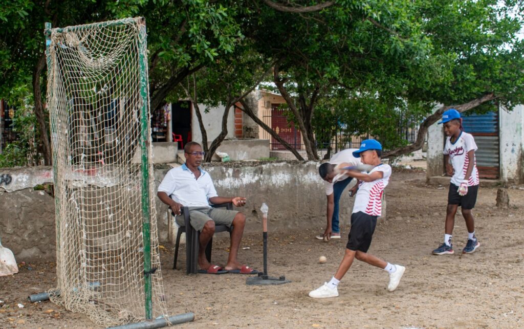 Piden intervención urgente. Entrenador y niños practicando béisbol en la cancha deteriorada de El Líbano.