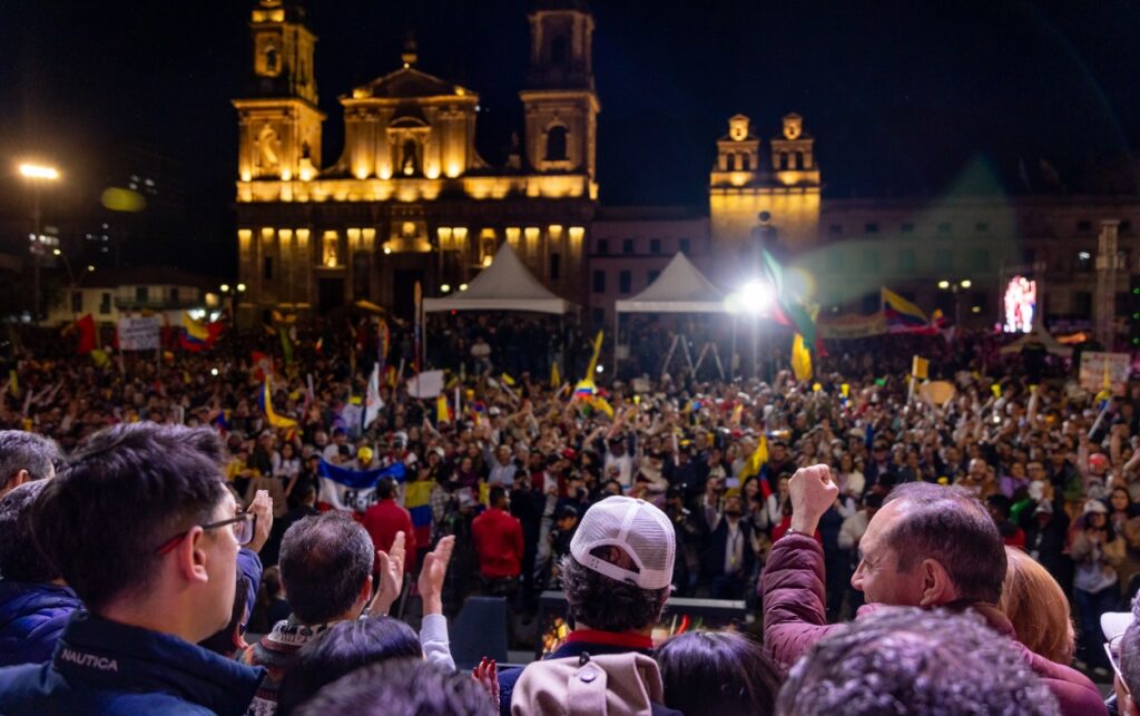 Ciudadanos levantan banderas en defensa del salario vital durante concentración nocturna en el centro de Bogotá.