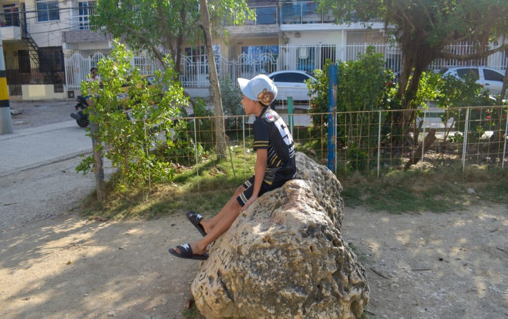 Niño sentado sobre la piedra insignia del parque en Los Cerezos, reflejo de Más de 40 años sin mejoras estructurales. 