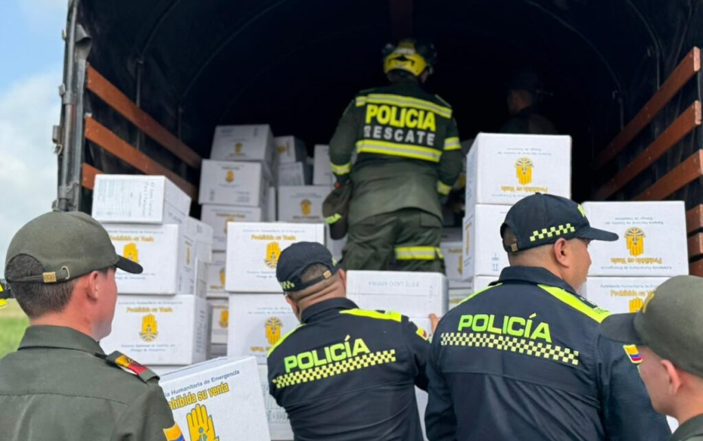 Uniformados de la Policía Nacional descargan kits humanitarios tras la llegada de 10 toneladas de ayuda a Córdoba.