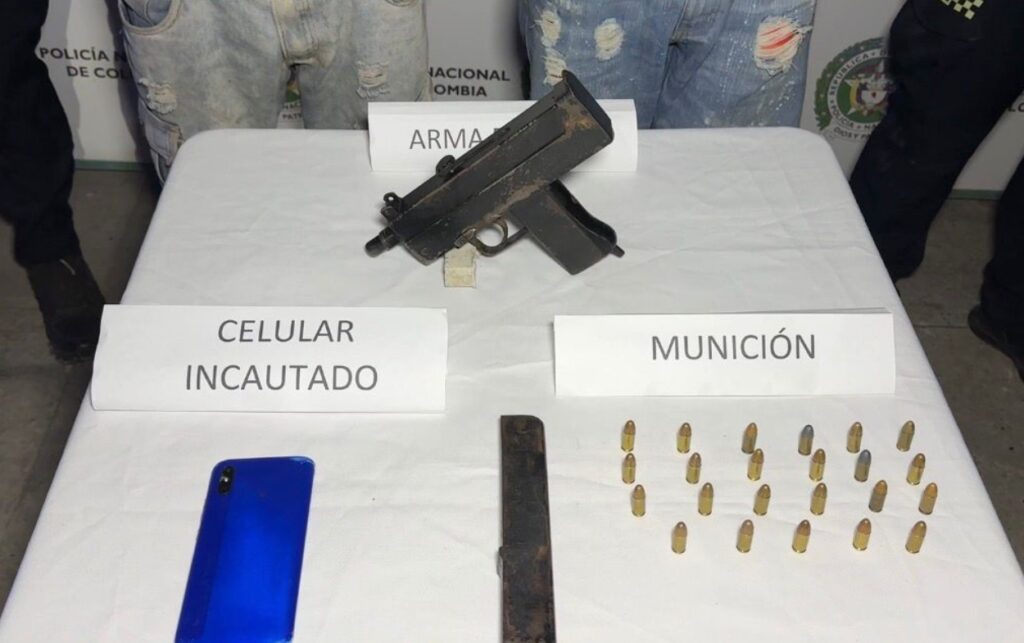 Evidencias incautadas por la Policía tras operativo en el que caen 2 presuntos delincuentes, entre ellas una subametralladora, munición y un celular. 