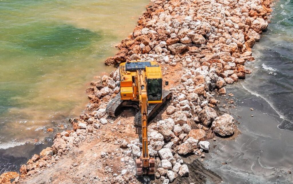 Maquinaria pesada trabaja sobre estructura de roca en Castillogrande, dentro de los 6,2 kilómetros de intervención que refuerzan la protección frente al mar.