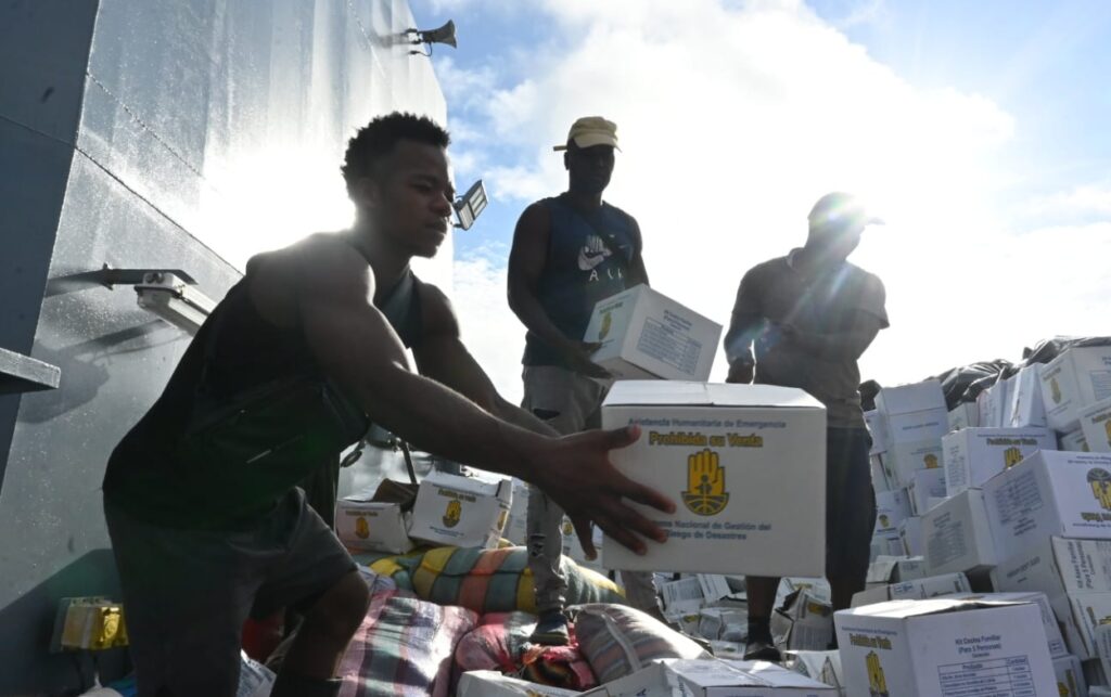 Distribución manual de kits humanitarios desde embarcación naval hacia comunidades afectadas por lluvias en el Pacífico colombiano.