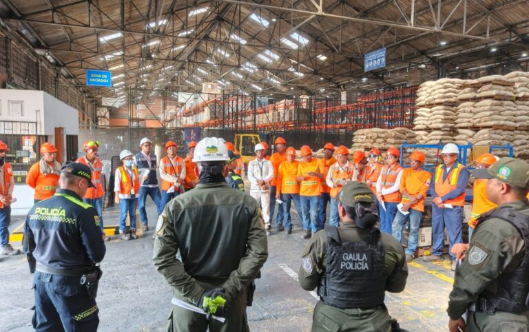 El Gaula de la Policía realiza capacitación frente a trabajadores del café en una bodega industrial llena de sacos apilados.