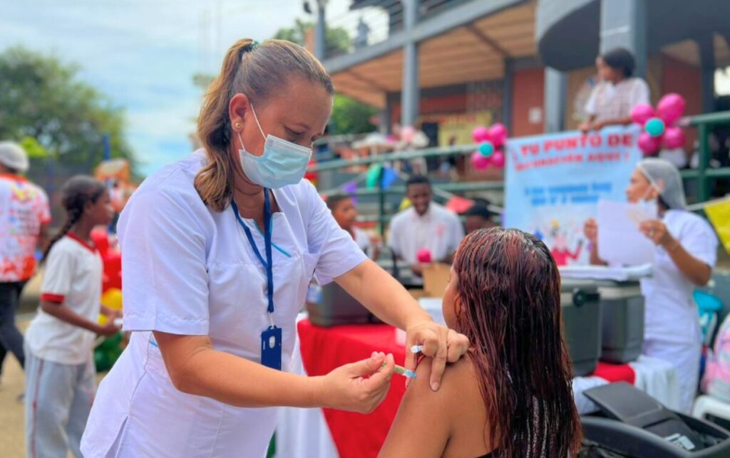Enfermera aplica una vacuna a una joven sentada en un punto comunitario durante la Jornada de Vacunación en Cartagena.