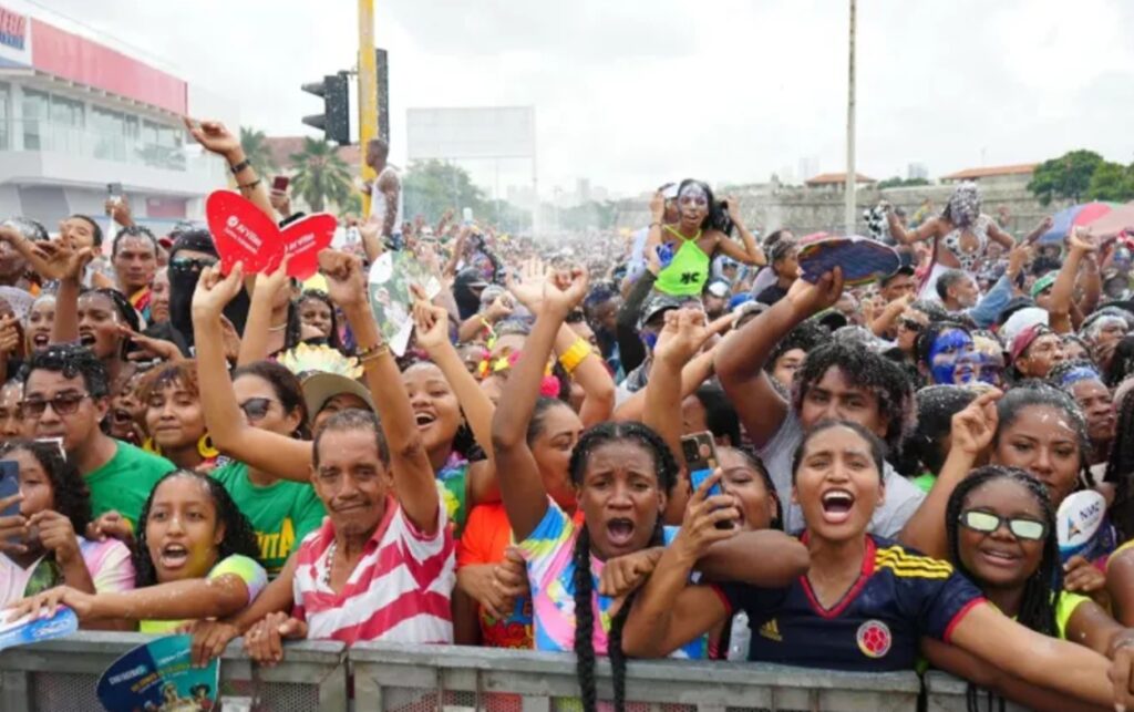Multitud celebrando durante las Fiestas de Independencia en Cartagena, con espuma y música en las calles del Arsenal.