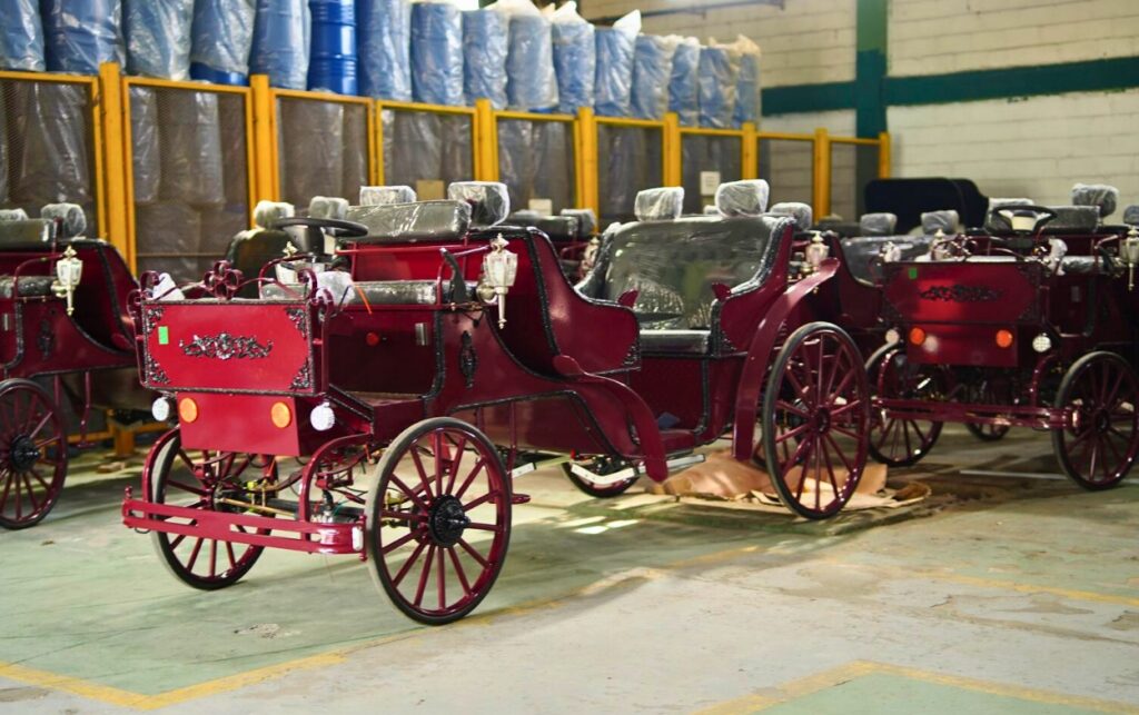 Coches eléctricos color vino tinto alineados en un taller industrial, listos para entrar en operación turística en Cartagena.
