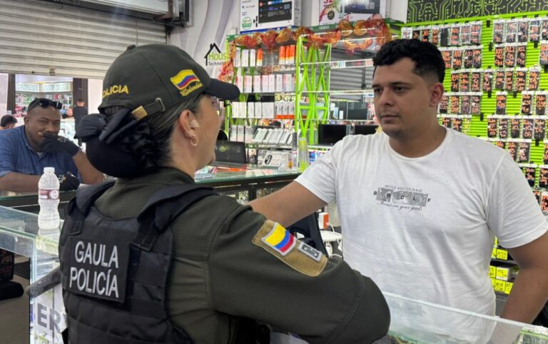 Funcionaria del Gaula orienta a comerciante sobre 165 la línea que permite denunciar extorsión en jornada preventiva en sector comercial de Cartagena.// Foto: cortesía- Gaula
