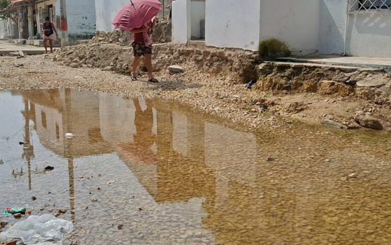 Claman solución en Boston_ habitante intenta cruzar tramo deteriorado de la calle 47 entre charcos y escombros, evidenciando el impacto diario de la obra paralizada.